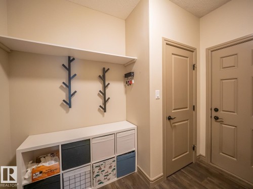 Built-in shelving unit with an upper shelf and lower cubbies, wood-finish flooring, and panel doors - 97 Astoria Point(E), Devon, AB - Indoor Photo Showing Other Room
