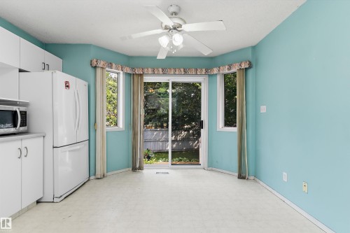 Kitchen area with white cabinetry, a built-in microwave, and a white refrigerator - 851 112A Street Nw, Edmonton, AB - Indoor