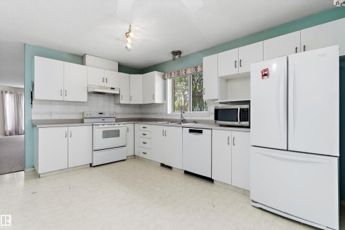 U-shaped kitchen featuring white cabinetry, light-toned countertops, and a white appliance package - 851 112A Street Nw, Edmonton, AB - Indoor Photo Showing Kitchen