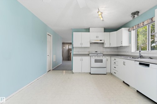 Kitchen featuring white cabinetry, a white electric range, a white dishwasher, a stainless steel sink, and a tiled backsplash - 851 112A Street Nw, Edmonton, AB - Indoor Photo Showing Kitchen