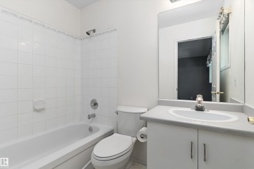 White tiled shower with a bathtub, toilet, and vanity with an integrated sink - 851 112A Street Nw, Edmonton, AB - Indoor Photo Showing Bathroom