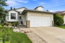 White siding exterior with a prominent bay window, attached garage, concrete driveway, and front landscaping featuring gravel and mature greenery - 851 112A Street Nw, Edmonton, AB  - Outdoor 