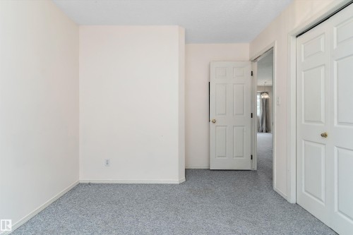 Neutral wall paint, light-colored carpeting, white paneled doors, and brass hardware - 851 112A Street Nw, Edmonton, AB - Indoor Photo Showing Other Room