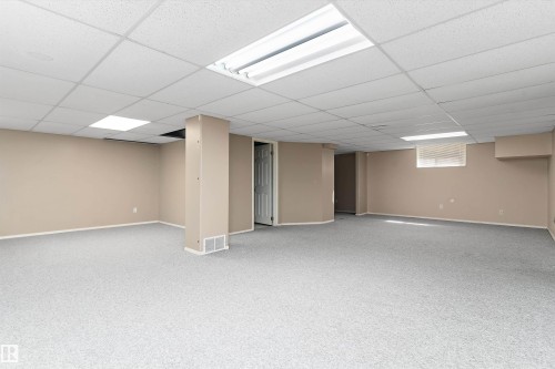 Expansive carpeted area with neutral-toned walls, drop ceiling, and recessed lighting - 851 112A Street Nw, Edmonton, AB - Indoor Photo Showing Basement