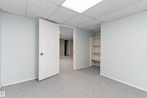 Versatile finished space featuring neutral wall finishes, carpeted flooring, recessed ceiling lighting, and built-in shelving - 851 112A Street Nw, Edmonton, AB - Indoor Photo Showing Other Room