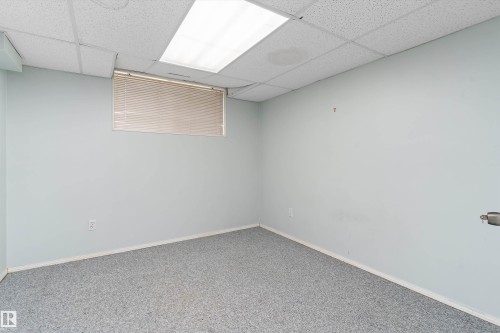 Recessed window with blinds, drop ceiling with integrated lighting, and neutral wall tones - 851 112A Street Nw, Edmonton, AB - Indoor Photo Showing Other Room