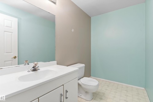 White vanity with integrated sink, chrome faucet, wall-mounted mirror, and patterned flooring - 851 112A Street Nw, Edmonton, AB - Indoor Photo Showing Bathroom