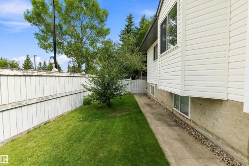 White vinyl siding, bay window, concrete foundation, mature green landscaping, and a privacy fence - 851 112A Street Nw, Edmonton, AB - Outdoor