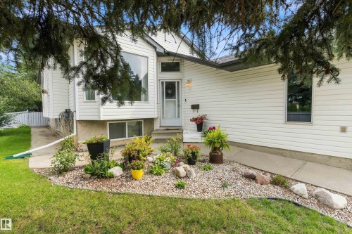 White siding exterior with a prominent bay window, front entry door, and a landscaped rock garden - 851 112A Street Nw, Edmonton, AB - Outdoor