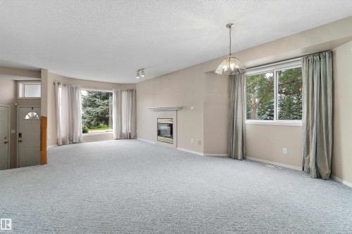Carpeted living space with a built-in fireplace, a bay window, and a decorative ceiling light fixture - 851 112A Street Nw, Edmonton, AB - Indoor With Fireplace