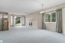 Carpeted living space with a built-in fireplace, a bay window, and a decorative ceiling light fixture - 851 112A Street Nw, Edmonton, AB  - Indoor With Fireplace 