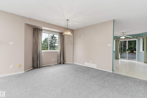 Carpeted flooring, pendant lighting, large window, sliding glass doors, and a ceiling fan - 851 112A Street Nw, Edmonton, AB - Indoor Photo Showing Other Room