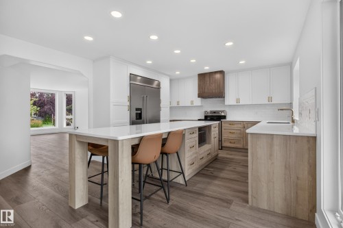 Modern kitchen featuring a large central island with seating, stainless steel appliances, recessed lighting, and wood-finish flooring - 229 Hillcrest Crest, Sherwood Park, AB - Indoor Photo Showing Kitchen With Upgraded Kitchen