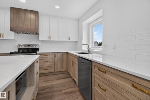 White cabinetry with gold-tone hardware, wood-finish lower cabinetry, white subway tile backsplash, white countertops, and wood-finish flooring - 229 Hillcrest Crest, Sherwood Park, AB - Indoor Photo Showing Kitchen With Upgraded Kitchen