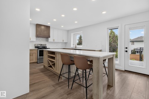 Kitchen featuring a large island with built-in wine storage, wood-finish flooring, white cabinetry, and stainless steel appliances - 229 Hillcrest Crest, Sherwood Park, AB - Indoor
