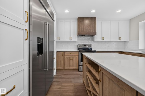 Stainless steel appliances, white subway tile backsplash, white shaker cabinetry, wood-finish flooring, and a central island with integrated wine storage - 229 Hillcrest Crest, Sherwood Park, AB - Indoor Photo Showing Kitchen