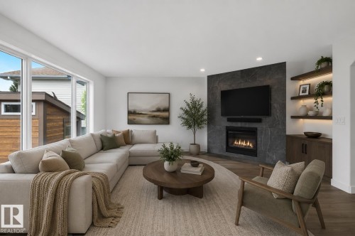 Spacious living area featuring large windows, a sleek wall-mounted fireplace with dark stone surround, wood-finish flooring, and built-in shelving with integrated lighting - 229 Hillcrest Crest, Sherwood Park, AB - Indoor Photo Showing Living Room With Fireplace