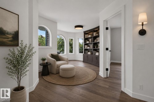 Wood-finish flooring, built-in shelving with integrated lighting, arched windows, and a wall-mounted sconce - 229 Hillcrest Crest, Sherwood Park, AB - Indoor