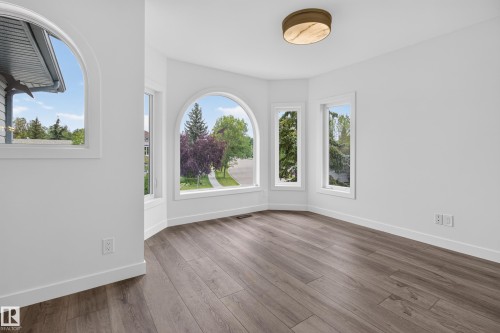 Bay window with an arched window, wood-finish flooring, white baseboards, and a flush-mount light fixture - 229 Hillcrest Crest, Sherwood Park, AB - Indoor Photo Showing Other Room