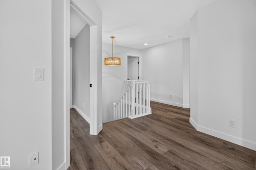 Wood-finish flooring throughout, white painted walls, white railing with square balusters, and a contemporary gold-tone chandelier - 229 Hillcrest Crest, Sherwood Park, AB - Indoor Photo Showing Other Room