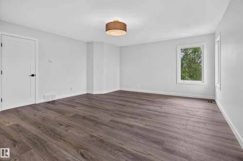 Spacious room featuring wood-finish flooring, a contemporary semi-flush ceiling light, and bright white walls - 229 Hillcrest Crest, Sherwood Park, AB - Indoor Photo Showing Other Room