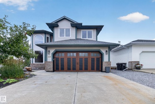 Two-story residence featuring light-colored siding, a dark shingle roof, and a wood-finish garage door with multiple panels - 229 Hillcrest Crest, Sherwood Park, AB - Outdoor