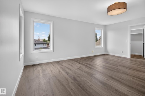 Spacious room featuring wood-finish flooring and multiple windows with white trim - 229 Hillcrest Crest, Sherwood Park, AB - Indoor Photo Showing Other Room