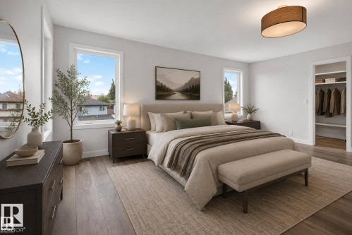 Bright primary bedroom featuring dual large windows with natural light, wood-finish flooring throughout, a dark wood nightstand with integrated lighting, and a walk-in closet with built-in shelving and hanging systems - 229 Hillcrest Crest, Sherwood Park, AB - Indoor Photo Showing Bedroom