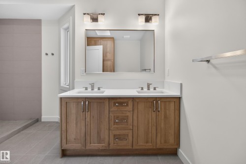 Dual sink vanity with wood-finish cabinetry, white countertop, and brushed nickel fixtures - 229 Hillcrest Crest, Sherwood Park, AB - Indoor Photo Showing Bathroom