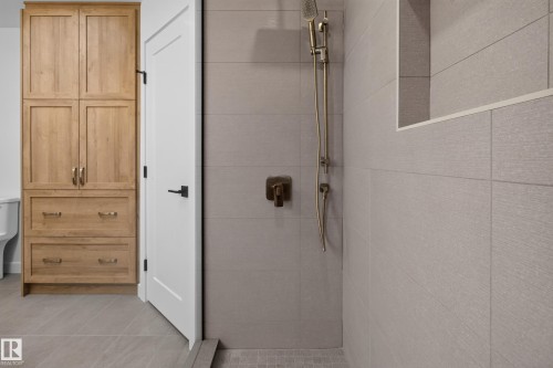 Built-in wood-finish cabinetry featuring brass hardware, full-height tiled shower, recessed shower niche, and matte brass shower fixtures - 229 Hillcrest Crest, Sherwood Park, AB - Indoor Photo Showing Bathroom