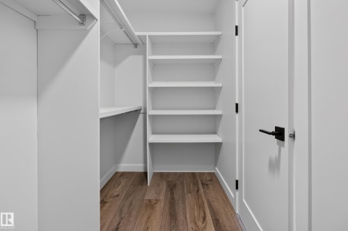 Built-in shelving, hanging rods, wood-finish flooring, and a white door with matte black hardware - 229 Hillcrest Crest, Sherwood Park, AB - Indoor With Storage