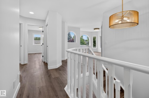 Wood-finish flooring, white spindle railing, arched windows, recessed lighting, and a drum pendant light fixture - 229 Hillcrest Crest, Sherwood Park, AB - Indoor Photo Showing Other Room