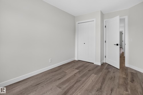 Wood-finish flooring, white bi-fold closet doors, white interior door with black hardware, and light neutral wall paint - 229 Hillcrest Crest, Sherwood Park, AB - Indoor Photo Showing Other Room