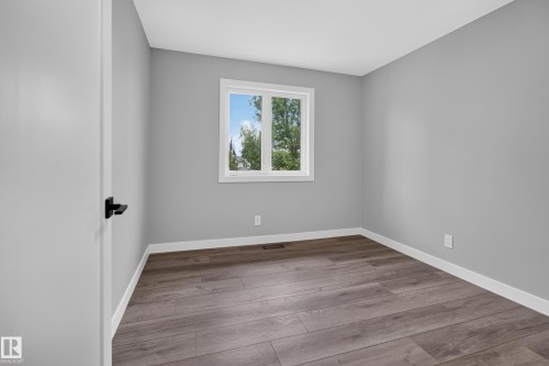 Wood-finish flooring with white trim, a double-hung window, and a matte black door handle - 229 Hillcrest Crest, Sherwood Park, AB - Indoor Photo Showing Other Room