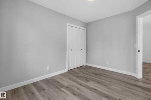Gray wall paint, wood-finish flooring, white bi-fold closet doors, white baseboards, and a ceiling-mounted light fixture - 229 Hillcrest Crest, Sherwood Park, AB - Indoor Photo Showing Other Room