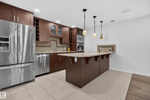Kitchen area featuring wood cabinetry, stainless steel appliances, a center island with pendant lighting, and a neutral tile backsplash - 229 Hillcrest Crest, Sherwood Park, AB - Indoor Photo Showing Kitchen With Stainless Steel Kitchen With Upgraded Kitchen