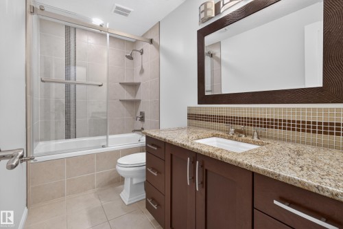 Tile shower/tub combination with sliding glass doors, dual corner shower shelves, and a decorative vertical accent - 229 Hillcrest Crest, Sherwood Park, AB - Indoor Photo Showing Bathroom