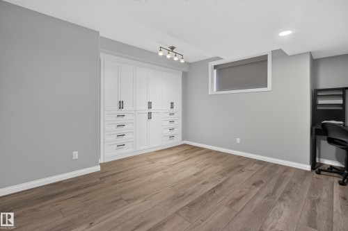 Wood-finish flooring, built-in white cabinetry with black hardware, recessed ceiling lighting, and a white window frame - 229 Hillcrest Crest, Sherwood Park, AB - Indoor Photo Showing Other Room
