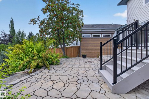 Expansive stone patio with irregular flagstone paving, a wood-finish fence, and mature landscaping - 229 Hillcrest Crest, Sherwood Park, AB - Outdoor