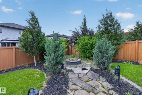 Landscaped backyard featuring a flagstone path, built-in stone fire pit, and mature trees - 229 Hillcrest Crest, Sherwood Park, AB - Outdoor