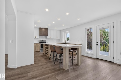 Kitchen island with integrated wine rack, wood-finish flooring, recessed lighting, white cabinetry, and stainless steel appliances - 229 Hillcrest Crest, Sherwood Park, AB - Indoor Photo Showing Other Room