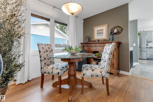 Wood-finish flooring throughout, featuring a built-in wooden buffet cabinet and a glass-top dining table - 6008 37 Avenue Nw, Edmonton, AB - Indoor Photo Showing Dining Room