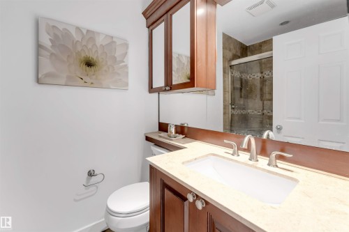 Built-in vanity with a light-toned countertop, undermount sink, and brushed nickel fixtures - 6008 37 Avenue Nw, Edmonton, AB - Indoor Photo Showing Bathroom