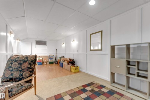 White paneled walls with sconce lighting, drop ceiling, recessed lighting, wood-finish flooring, and carpeted area - 6008 37 Avenue Nw, Edmonton, AB - Indoor Photo Showing Other Room
