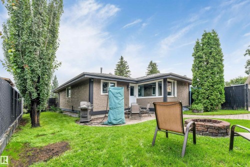 Expansive green space featuring a paved patio area, a built-in stone fire pit, and mature perimeter trees - 6008 37 Avenue Nw, Edmonton, AB - Outdoor