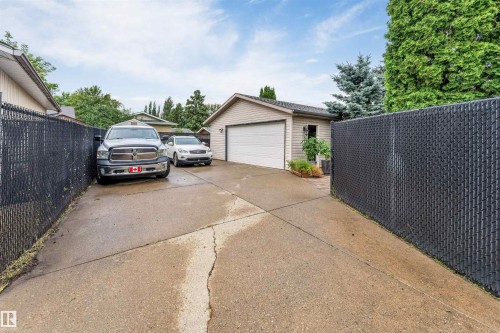 Detached garage with a white overhead door, concrete driveway, and mature landscaping - 6008 37 Avenue Nw, Edmonton, AB - Outdoor