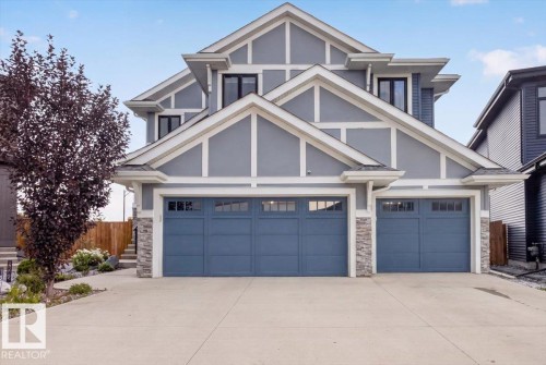 Contemporary facade featuring multiple gables, a two-car garage with individual doors, stone accent pillars, and a concrete driveway - 6813 Knox Loop Sw, Edmonton, AB - Outdoor With Facade