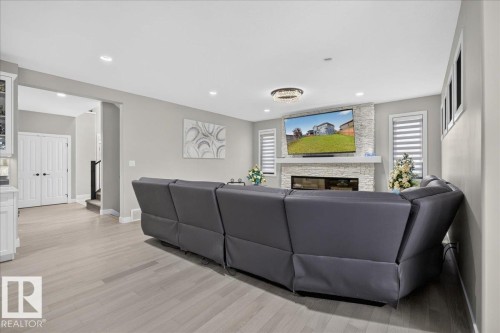 Recessed lighting, wood-finish flooring, and a stacked stone fireplace with a white mantel - 6813 Knox Loop Sw, Edmonton, AB - Indoor Photo Showing Living Room With Fireplace