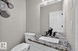 Vanity with a speckled countertop and integrated sink, matte black fixtures, and a wall-mounted mirror with overhead lighting - 