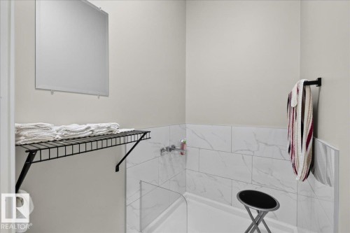 Walk-in shower with clear glass partition, white subway tile surround, and built-in wall shelving - 6813 Knox Loop Sw, Edmonton, AB - Indoor Photo Showing Bathroom